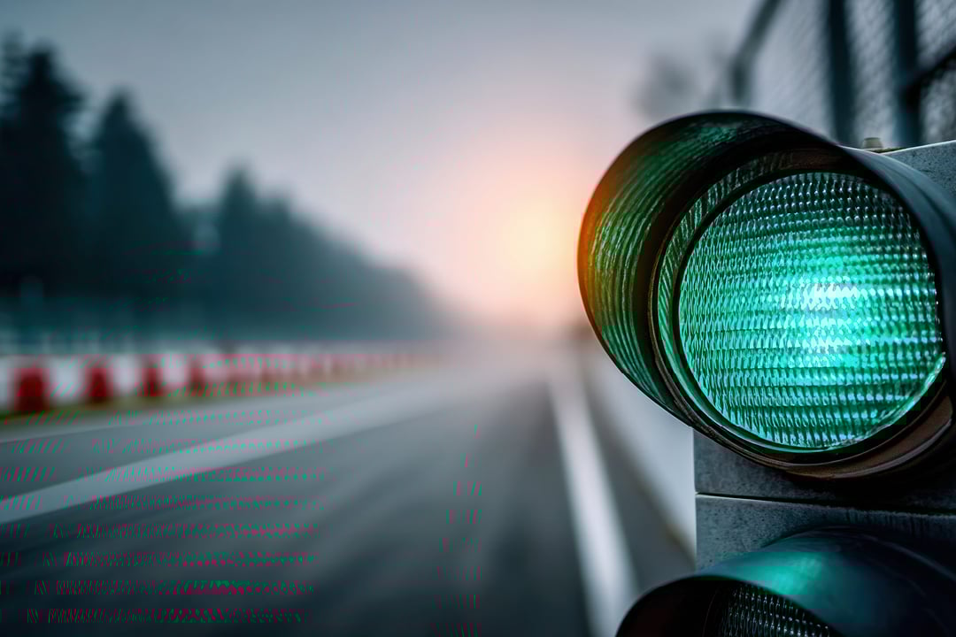Green racetrack start light glowing in fog with track fading into mist