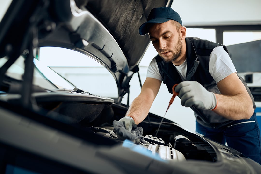 Mechanic checking engine oil level in car