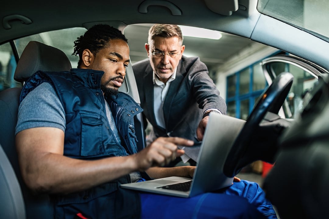 African American mechanic and customer using a laptop in an auto repair shop