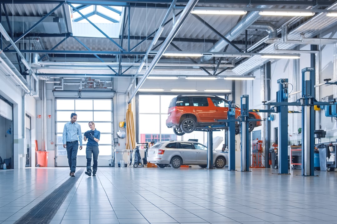 Female mechanic reviewing car diagnostics on tablet with manager