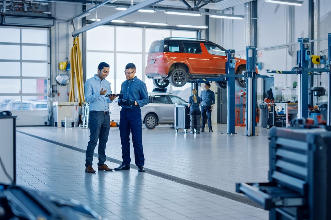 Auto repair shop owner and manager reviewing business performance data on a tablet