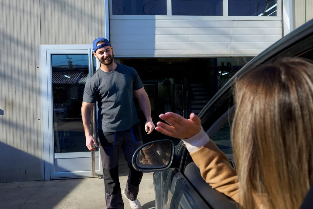 Mechanic greeting woman arriving for auto repair service