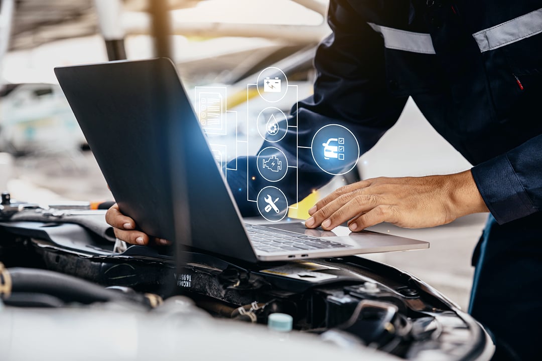 Mechanic checking engine parts on laptop in auto repair shop