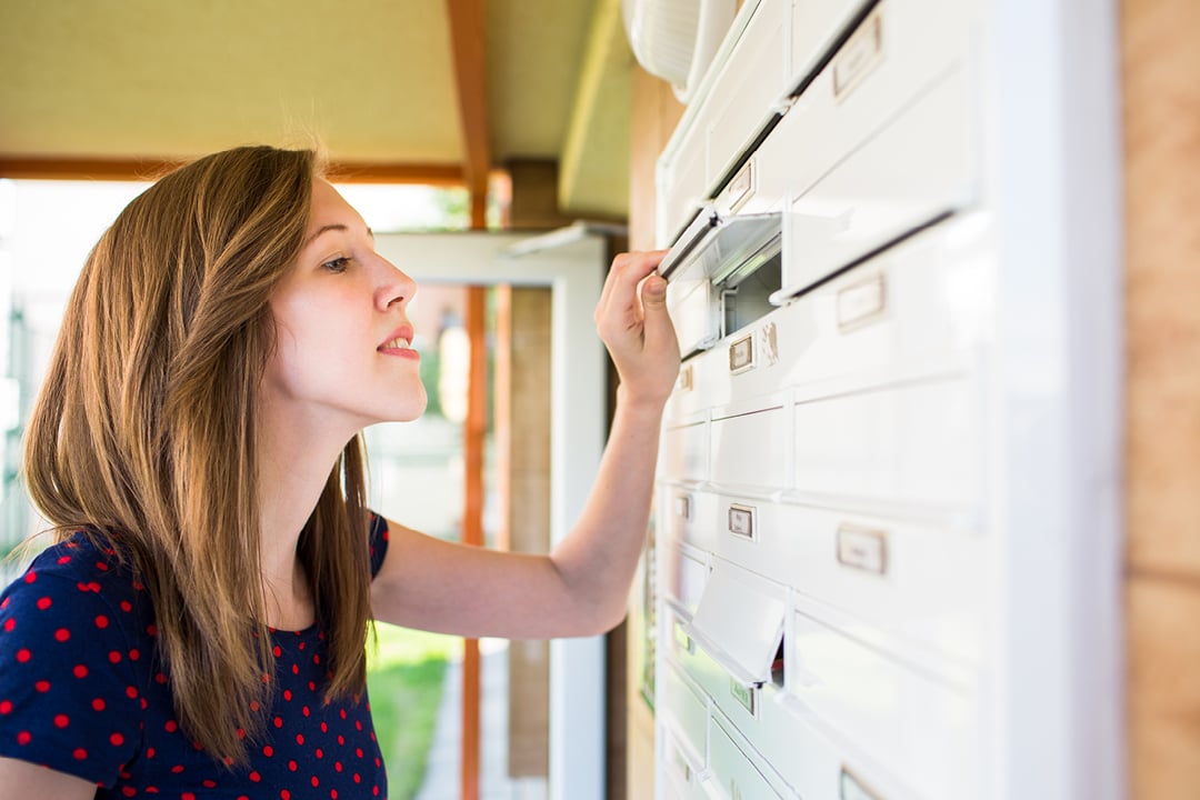 Young woman checking residential mailbox for mail