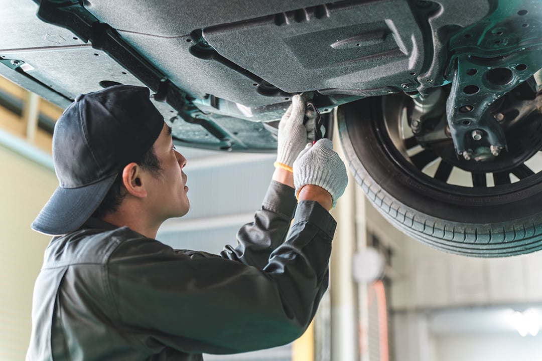 Mechanic performing maintenance under car on lift