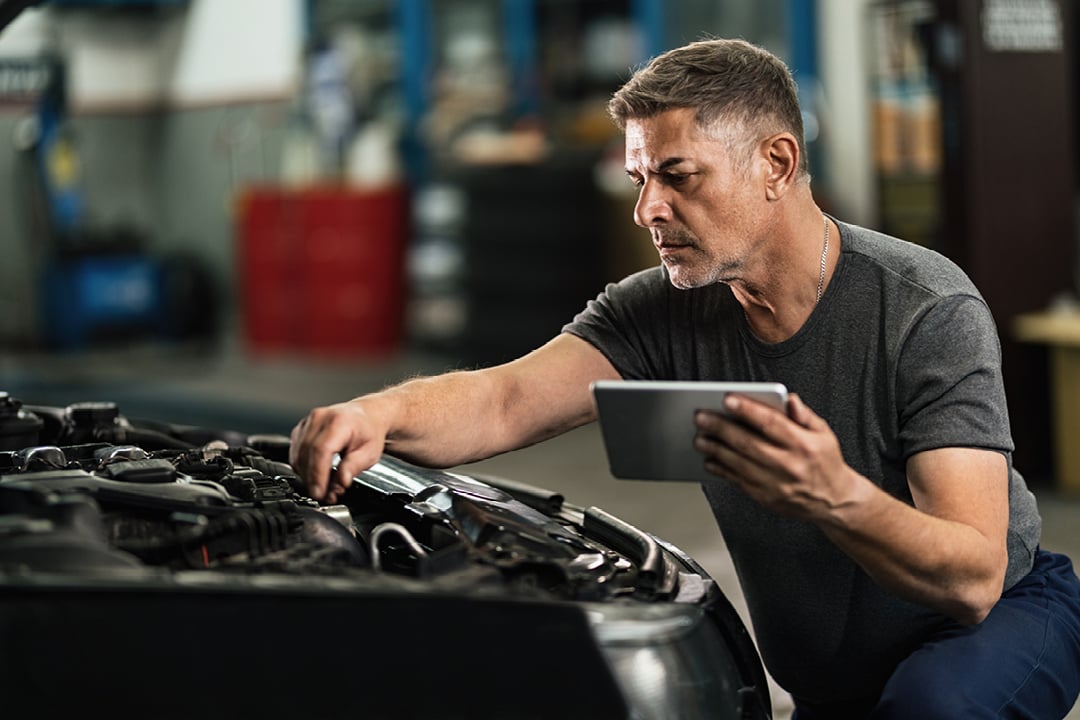Mechanic examining engine using a digital tablet