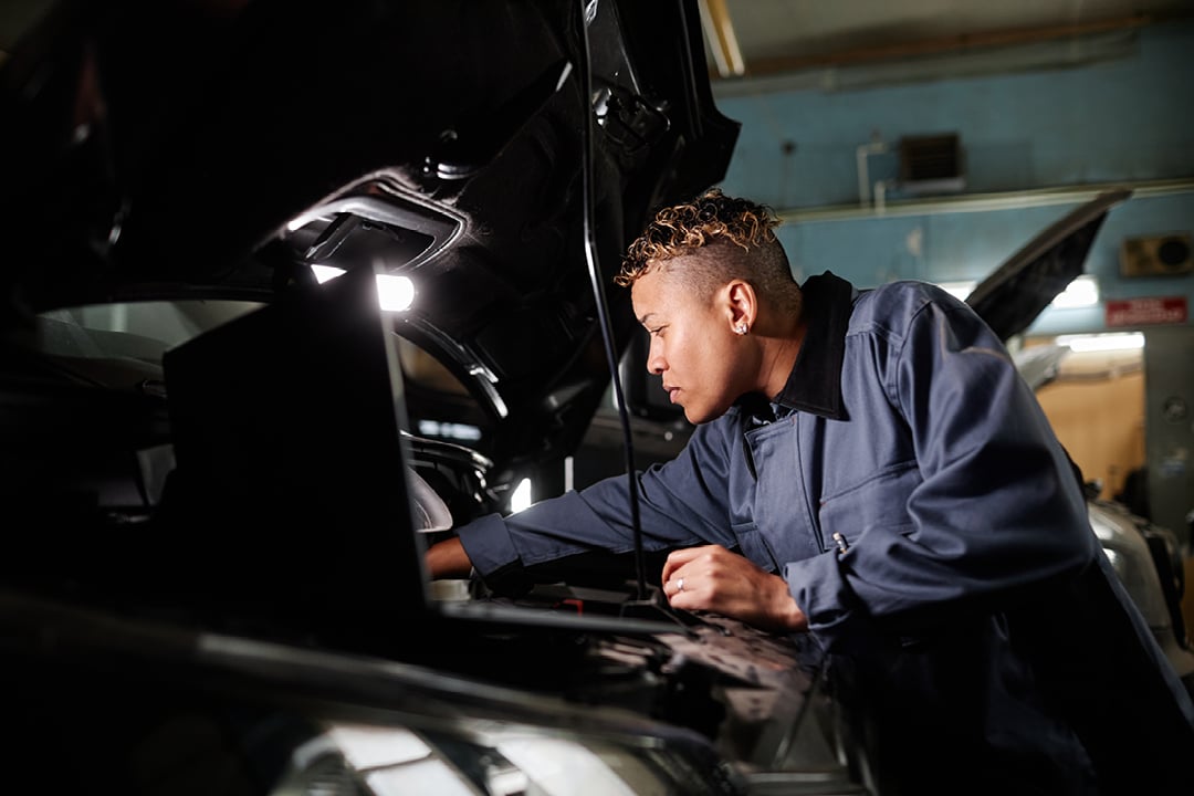 Female mechanic repairing truck engine in garage