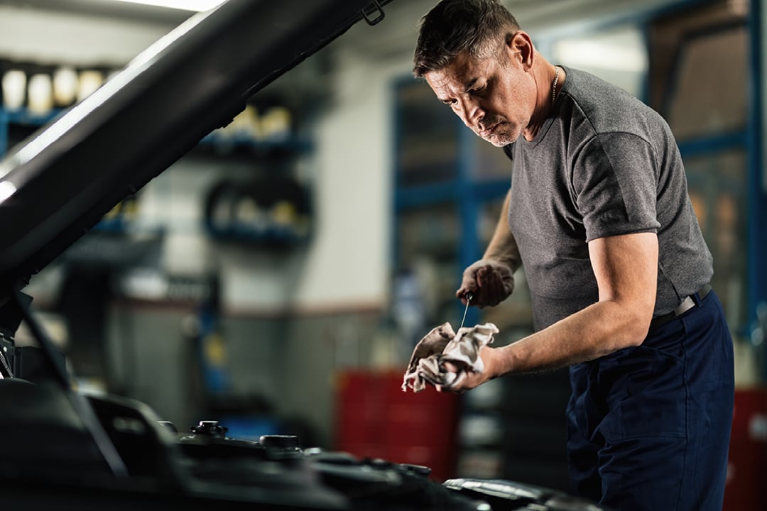 Mechanic checking engine oil level at auto repair shop