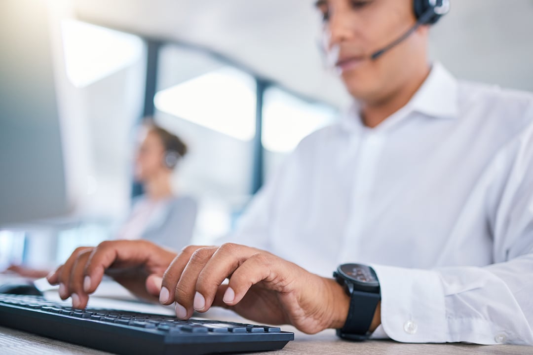 Call center agent typing on keyboard while speaking on headset